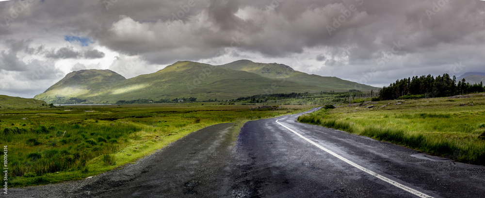 Wall mural road in connemara national park ireland with stormy clouds