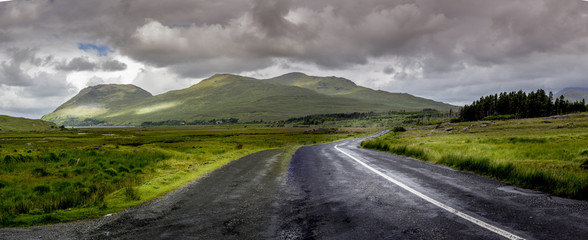 Road in Connemara national park Ireland with stormy clouds