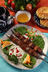 Kebab of beef liver with sheep's tail fat.Served with chopped spring onions with pomegranate,herbs and lemon.Uzbek cuisine.The upper projection