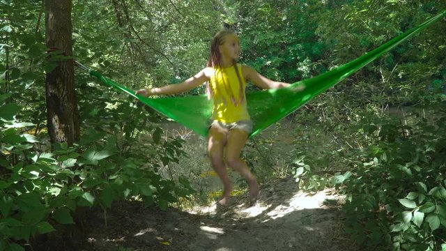 Pretty young girl swinging on hammock. Summer Holidays in the Green Forest