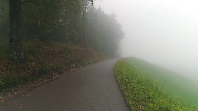Flying low over a road moving through the dense fog in Skofja Loka Slovenia.