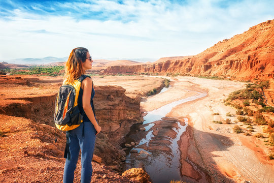 Young woman looking at beautiful landscape. Nature of Morocco view from above. Traveler girl stands on a rock looks up at the valley of Ounilla