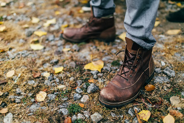 A pair of brown hiking boot in autumn forest. Soft focus on boot - 180108911