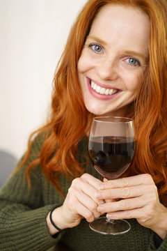 lachende frau hält ein glas rotwein in der hand