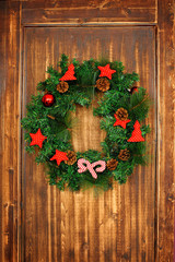 Christmas wreath on wooden door decoration. fir branches with Christmas toys for the new year