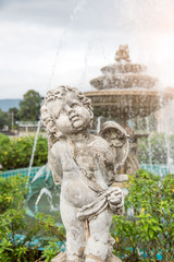Cute little child sculpture decorate in front of fountain in the garden .