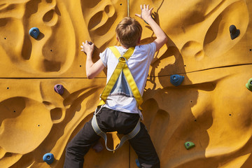 Child climbing a rock wall outdoor - bouldering