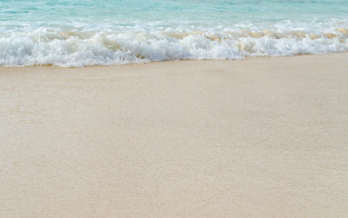 Close up Wave of The Ocean, White Sand on Summer Beach and Surface Water Foam.