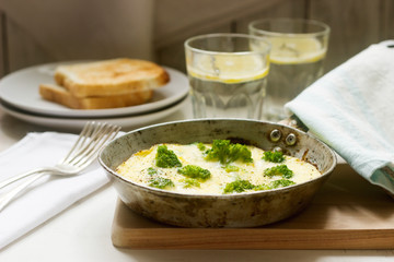 Omelette with broccoli and cheese served with bread toasts and lemonade.