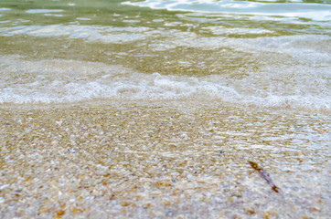Fototapeta na wymiar Close up Wave of The Ocean, White Sand on Summer Beach and Surface Water Foam.