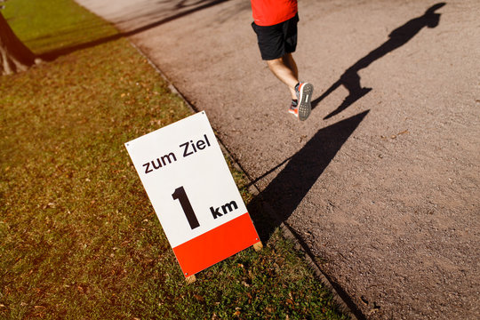 L&auml;uferbeine in der Abendsonne mit Schild bis Ziel. 