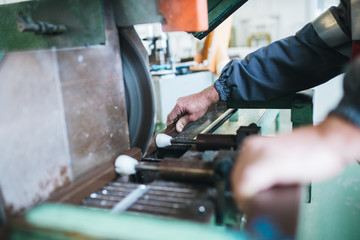 Manual worker cutting aluminum and PVC profiles. Manufacturing jobs. Selective focus. Factory for aluminum and PVC windows and doors production.