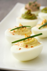 Variety of stuffed eggs with avocado and tuna on wooden table