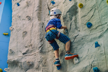 little boy climbing wall in sport center