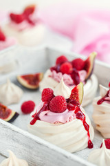 Delicious mini Pavlova meringue cake decorated with fresh raspberry, figs  and berry sauce