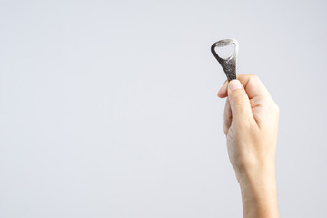 Hand holding classic bottle cap opener made of steel