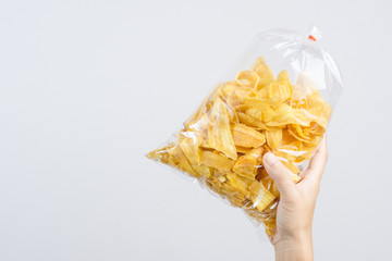 Hand holding fried sliced banana chip in food plastic bag tied by rubber