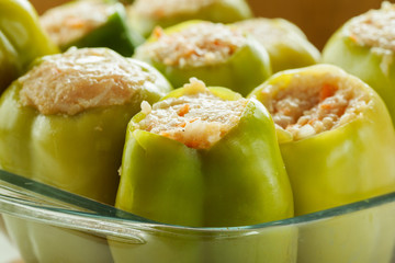 Fresh green bell peppers stuffed with meat with rice in a glass dish