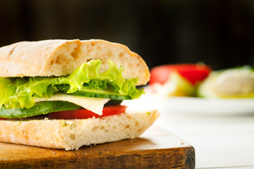 Vegetarian sandwich with avocado, tomato, egg and green salad on a wooden board