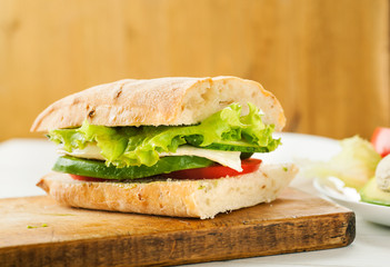 Vegetarian sandwich with avocado, tomato, egg and green salad on a wooden board