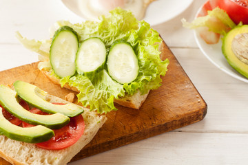 Sliced avocado, tomatoes, cucumber on a fresh ciabatta bread