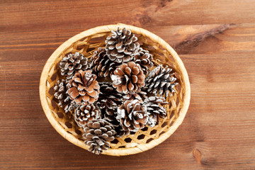 Obraz na płótnie Canvas Dry fir tree cones in a wicker basket on a wooden table