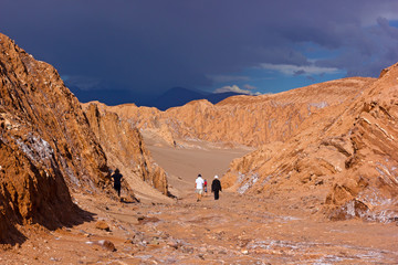 Approaching thunder in Atacama Desert, Chile. Tourists explore rock formations and sandy hills on the deserted landscape.