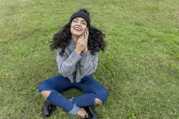 Woman calling on phone sitting on the grass