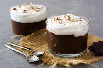 Chocolate mousse with cream in glass on gray stone