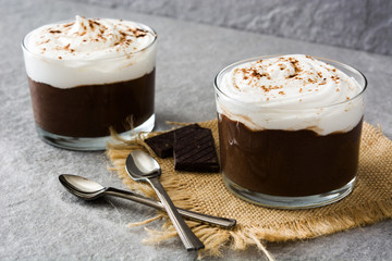 Chocolate mousse with cream in glass on gray stone