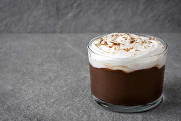 Chocolate mousse with cream in glass on gray stone.Copyspace