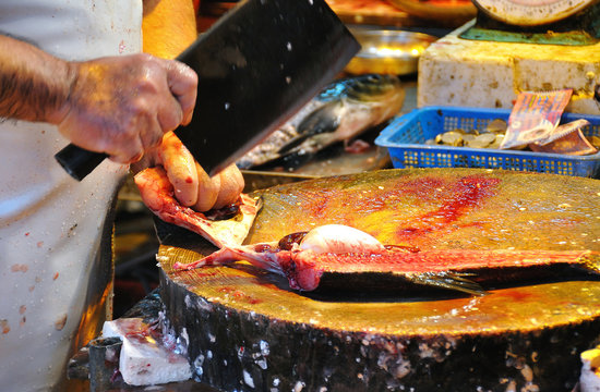 Fishmonger Slicing Up A Fish At A Hong Kong Wet Market