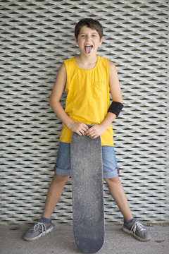 A teenage boy carrying skateboard and smiling