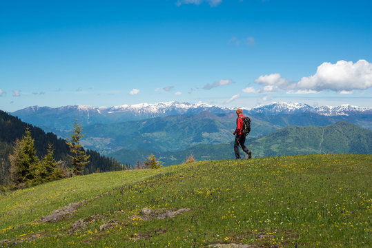 Traveler walks along mountain green meadow