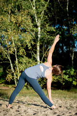 Woman practicing yoga in the sand - Triangle Pose - Utthita Trikonasana - Autumn day