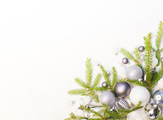 Christmas or New Year background: silver glass toys and balls, fir tree branches, decoration on white background. 