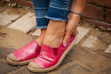 Young female touching her rubbed foot. New shoes cause sore skin on foot, rubbing foot blister...