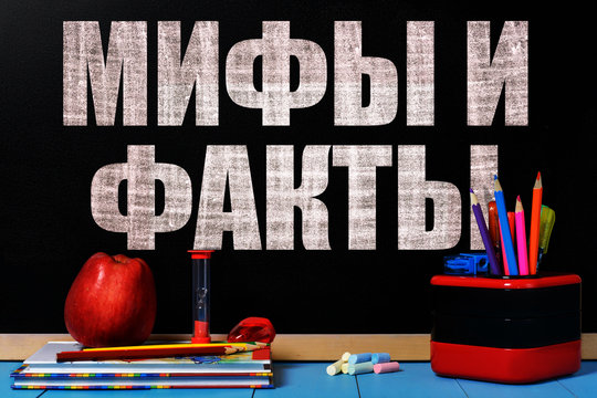 Text Myths and Facts (russian language) on black chalkboard with school accessories