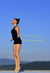 Woman gymnast in black sportswear with green jump rope