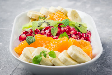 Healthy vegan fruit dessert with mint and lemon dressing on stone background. Selective focus, close up. 