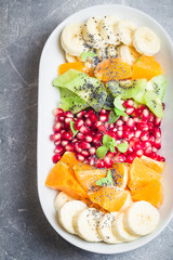 Honey lime rainbow fruit salad on stone, concrete background. Top view, copy space.