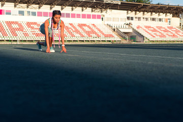 Beautiful young caucasian sport girl ready to run at the starting point. Healthy runner woman getting started to run in a morning. Active sporty girl at starting line.