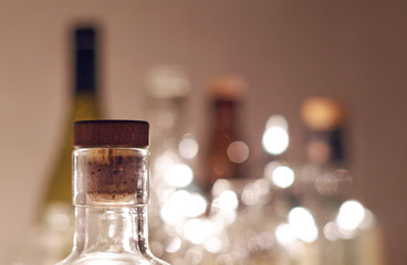 Vintage clear glass liquor bottles with cork in focus with plain background and Christmas lights