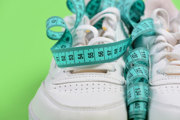 Centimeter in cyan blue color curled on white trainers, closeup