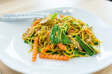 Fried yellow noodles with pork in white dish