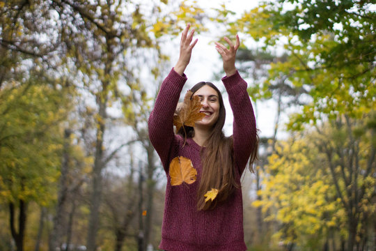 girl at a park thowing leaves in the air autumn scenery yellow leaf fall