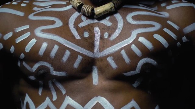 Black man in white patterns strains chest muscles