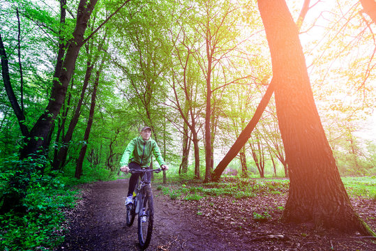 A man rides a bicycle through the woods