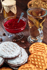 cookies with white chocolate frosting and raspberry jam in a little vase on the table for tea