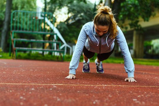Slim beautiful athletic woman doing pushup exercise.